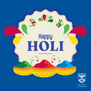 Dark blue background, text reads 'Happy Holi'. A red, blue and green pot of coloured paint powder sit below the text.